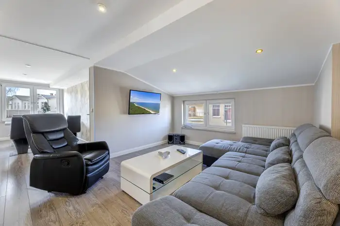 Moderner Wohnbereich einer Ferienwohnung Ahlbeck mit Ecksofa, Fernsehsessel und Flachbild-TV